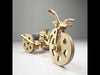 DIY wooden tricycle model kit with laser-cut frame, three wheels, small electric motor, battery holder, and wires – educational STEM toy for kids and hobbyists.