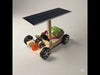 A set of DIY solar car kit components including pre-cut wooden chassis parts, a solar panel, electric motor, four wheels, two axles, screws with small tools, and wires for electrical connections
